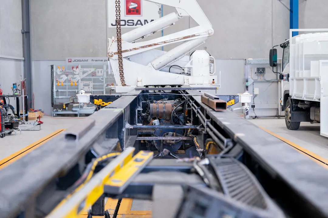 Truck chassis undergoing frame and mechanical repair in a workshop